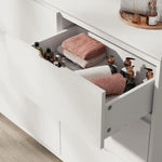 Open white bathroom drawer of bedroom dresser with anti-toppling device for safety