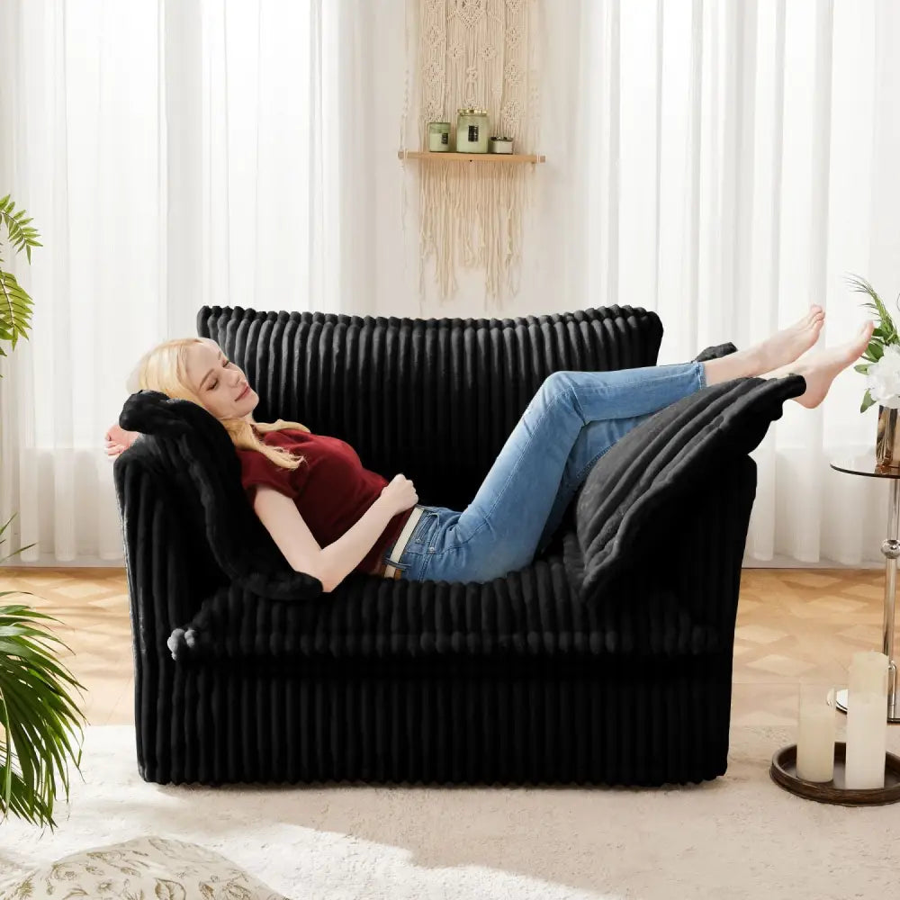 Black corduroy deep seat modern sofa with a reclining woman lounging peacefully