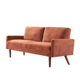Salmon-colored velvet couch with wooden legs for a chic living room setting