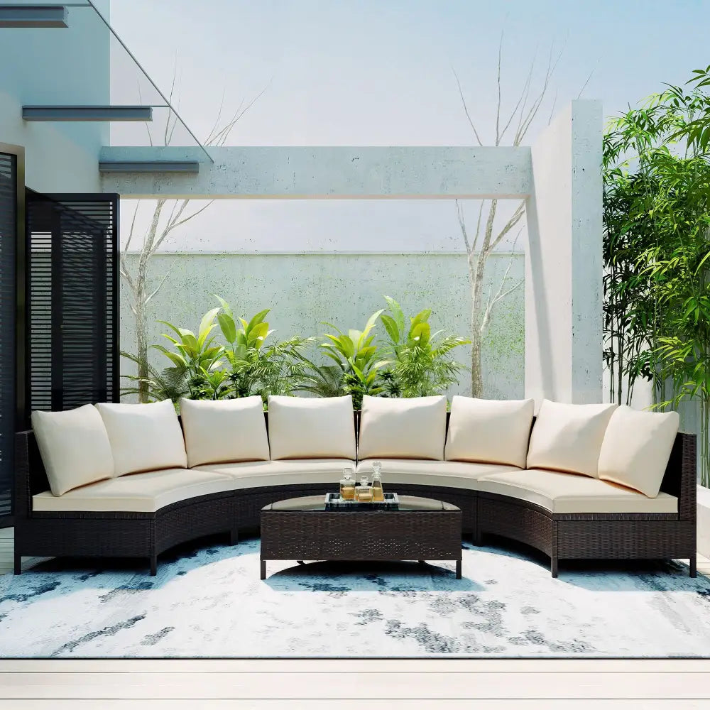 Curved wicker sectional sofa set with cushions and glass table for outdoor patio use