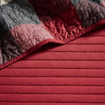 Red and herringbone patterned quilted fabric on a reversible daybed cover set